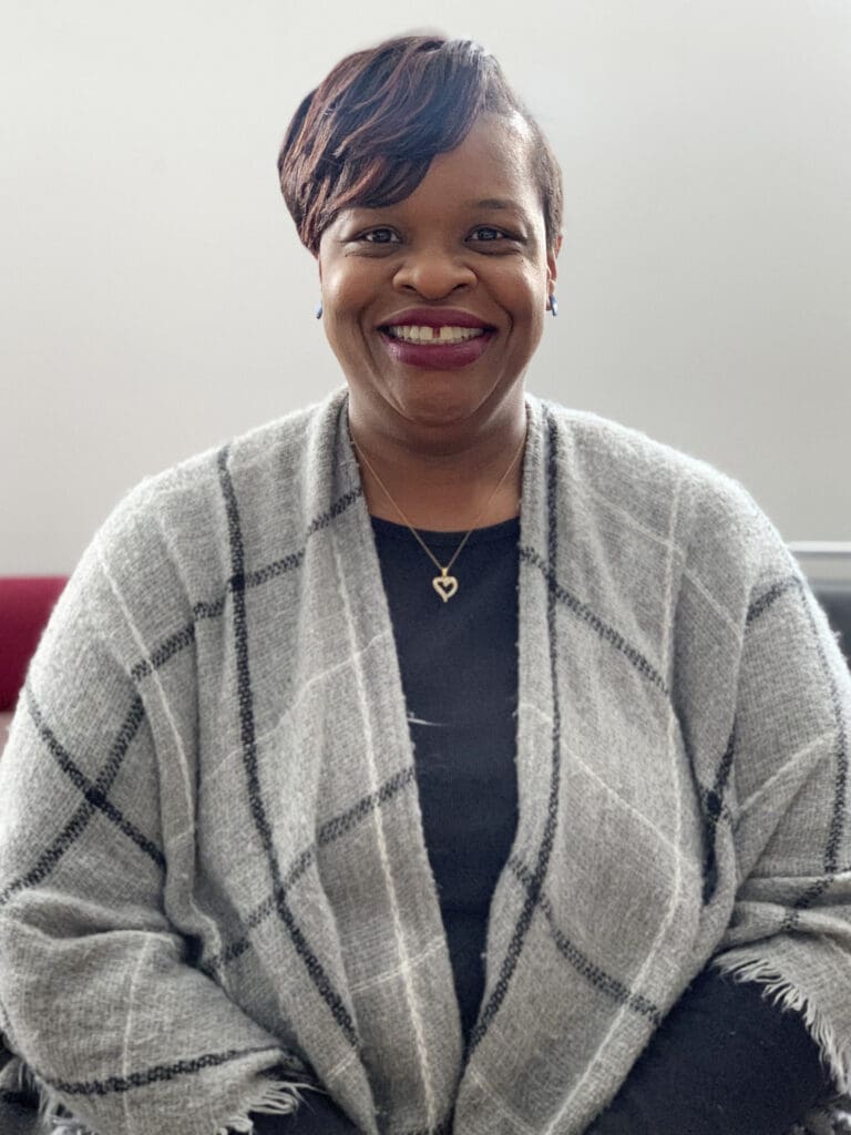 A woman in a gray jacket smiling for the camera.