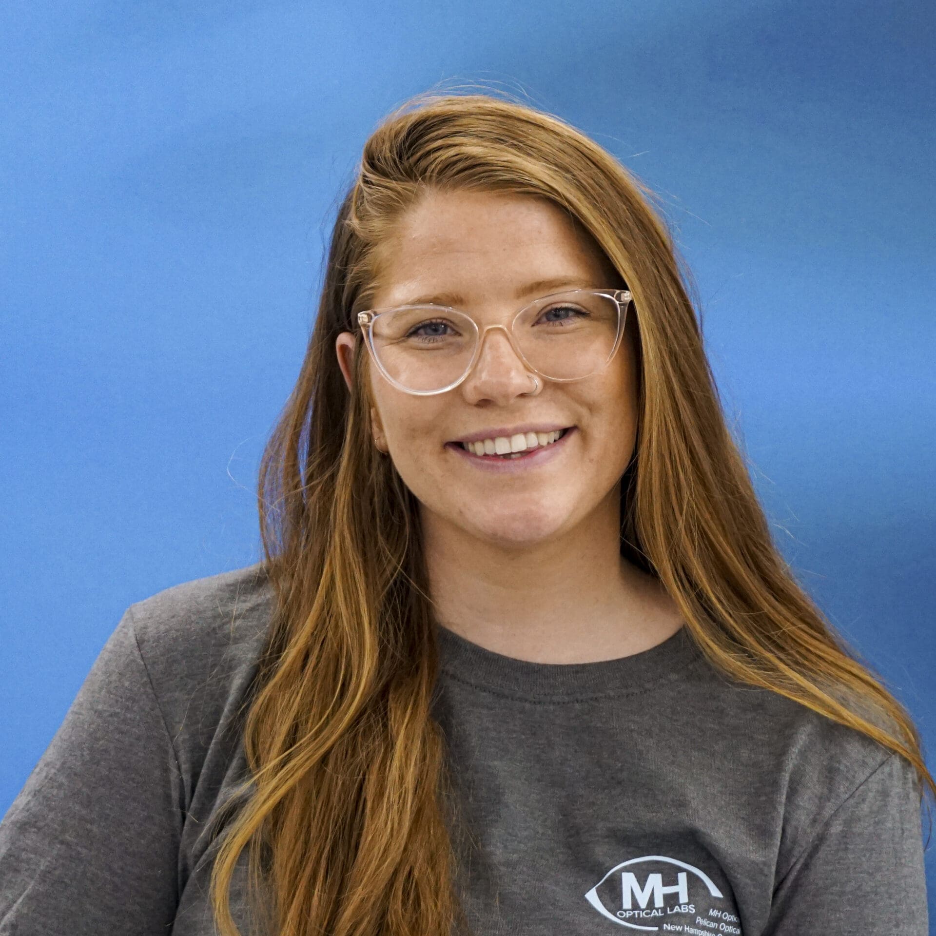 A woman with long hair wearing glasses and smiling.