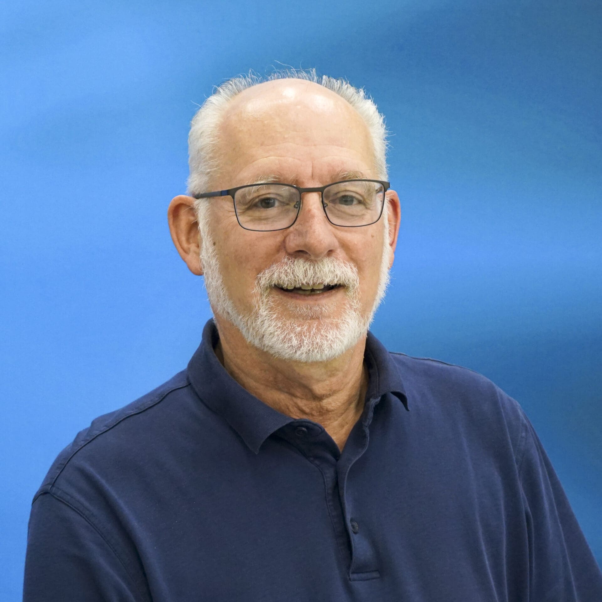 A man with glasses and a beard wearing a blue shirt.