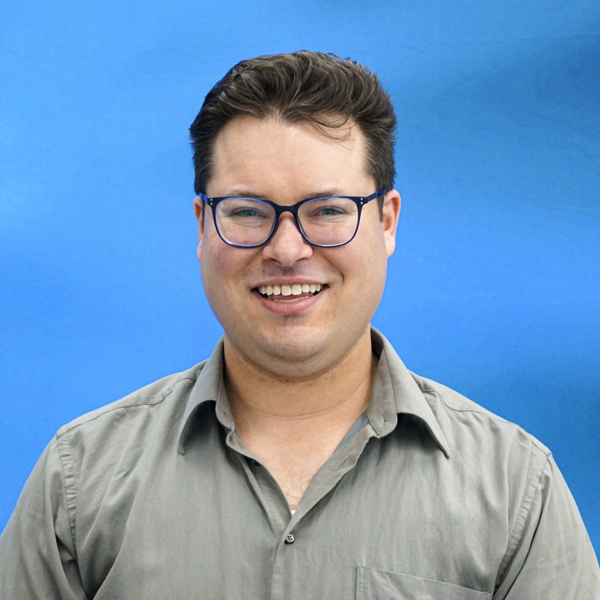 A man with glasses smiling for the camera.