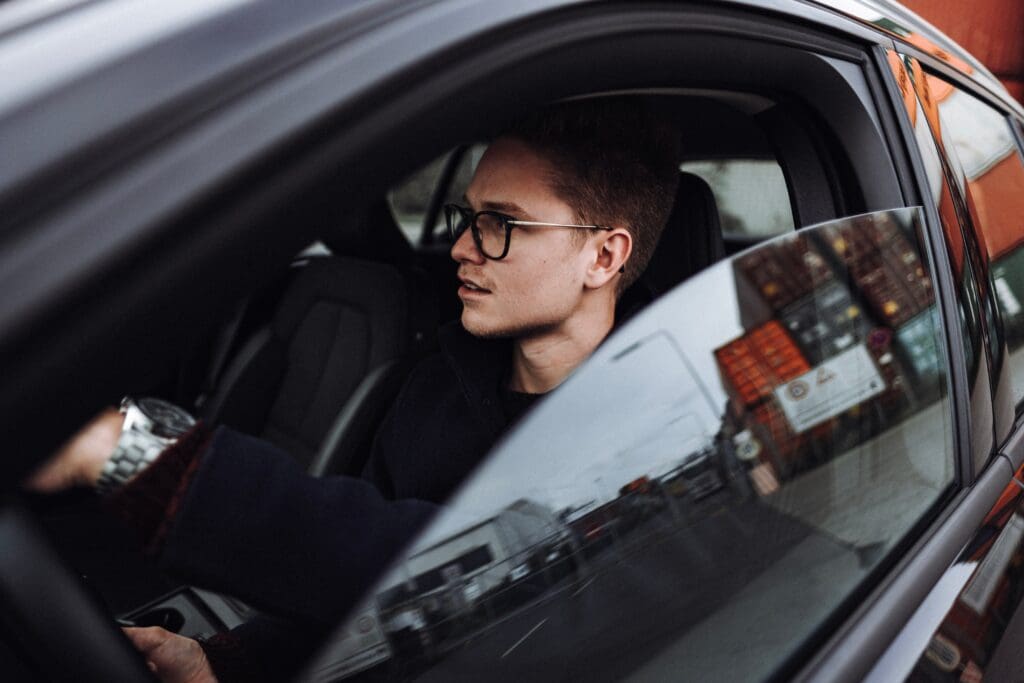 A man sitting in the driver 's seat of his car.