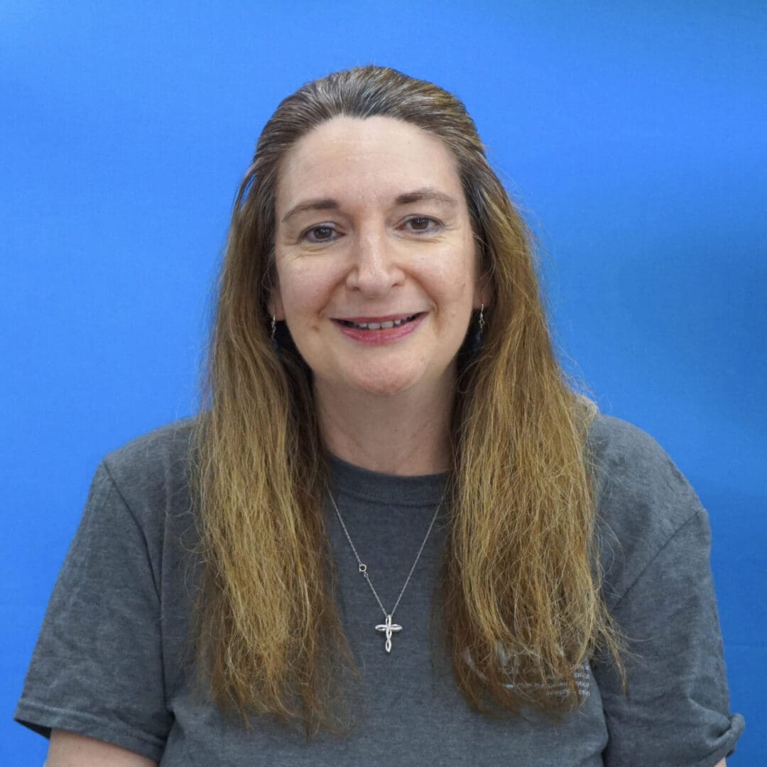 A woman with long hair wearing a gray shirt.