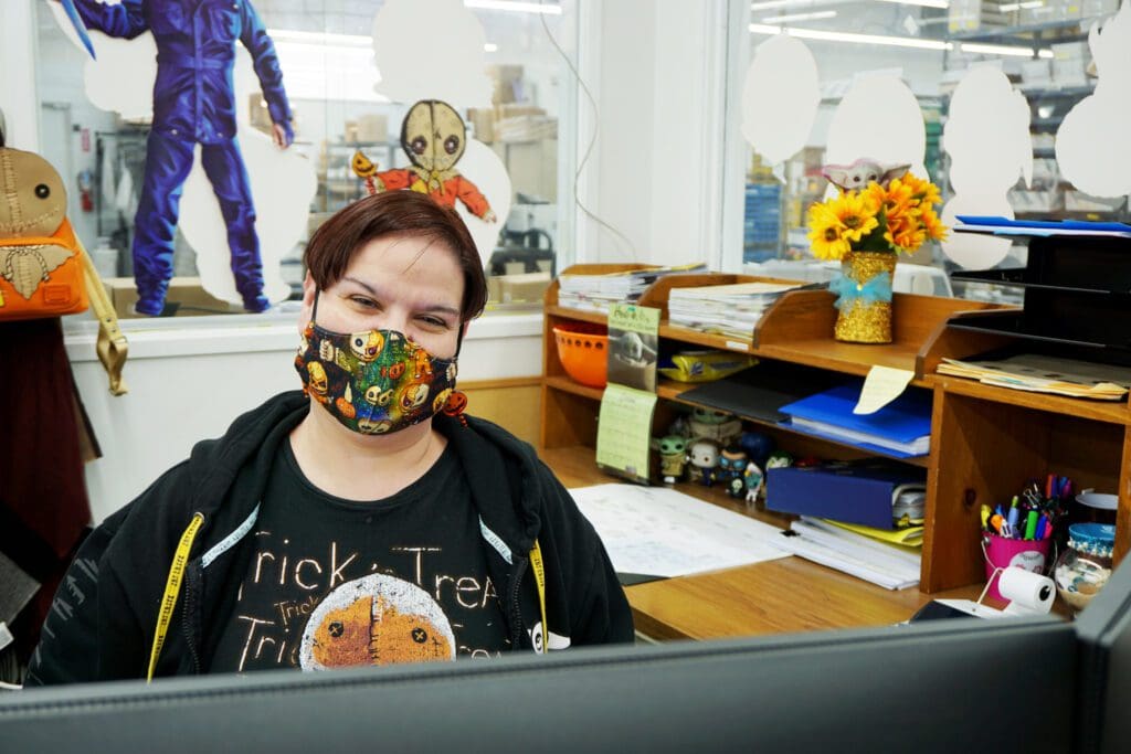 A woman wearing a mask while sitting at her desk.