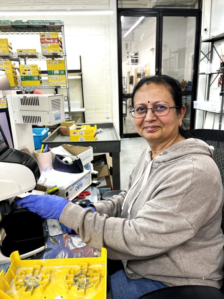 A woman in glasses and gloves working on something.