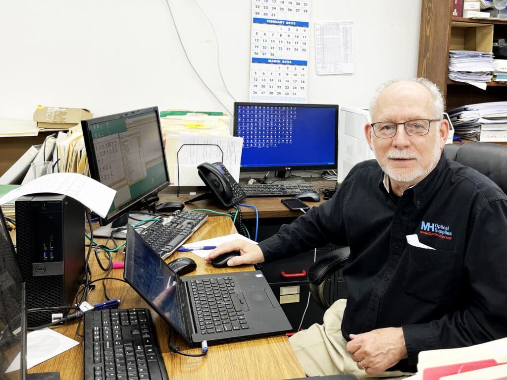 A man sitting at his desk with several computers.