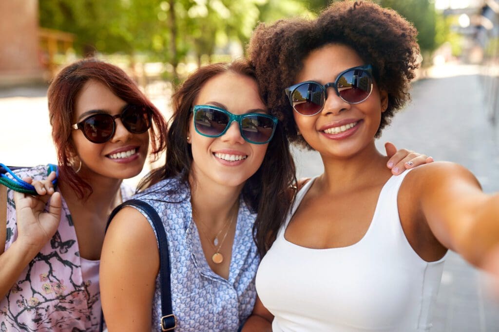 Three women posing for a picture in sunglasses.